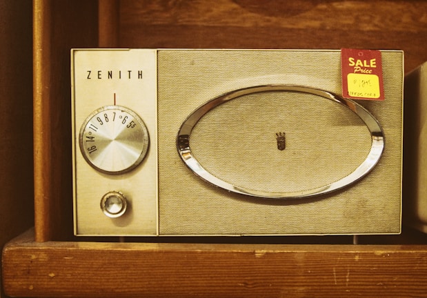 A vintage Zenith radio with a tuning dial and speaker grille, set within a wooden shelf. A 'Sale' tag with a handwritten price is attached to the radio.