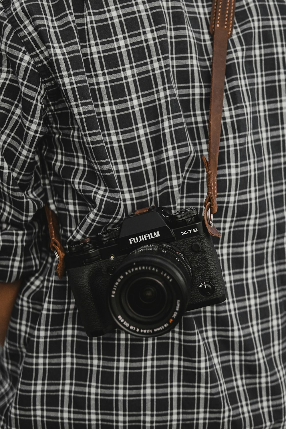 Cámara réflex Nikon negra sobre textil a cuadros blancos y negros