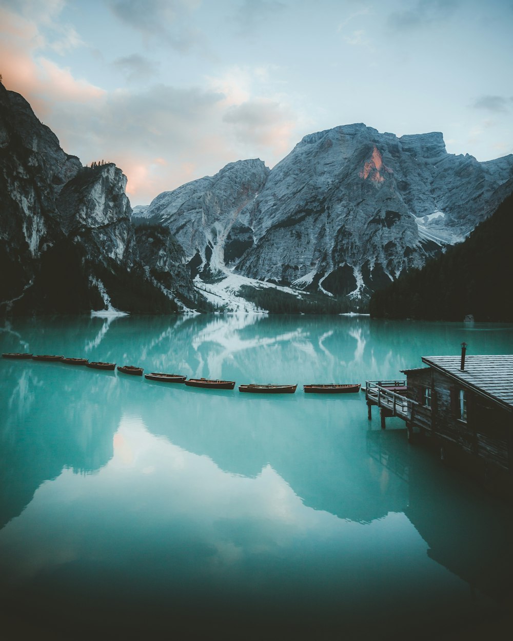 Muelle de madera marrón en el lago cerca de la montaña cubierta de nieve durante el día