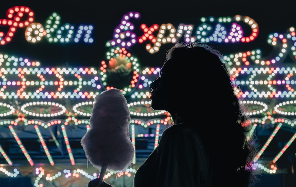 silhouette of woman standing near lighted christmas tree during night time