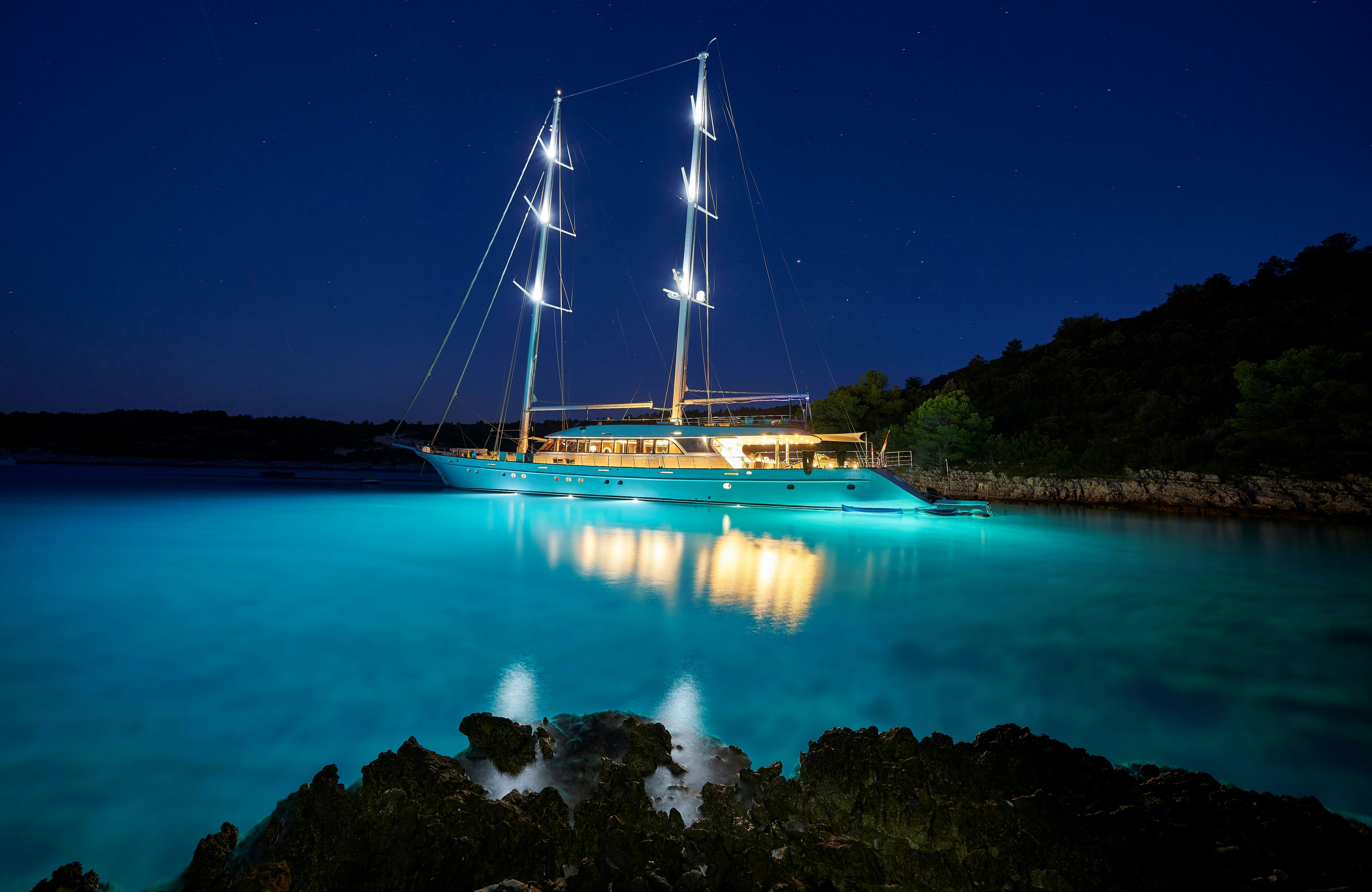 brown and white sail boat on blue body of water during night time