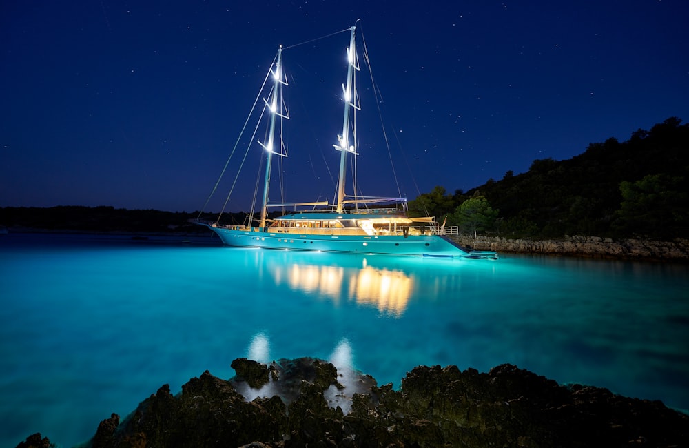 veleiro marrom e branco no corpo de água azul durante a noite