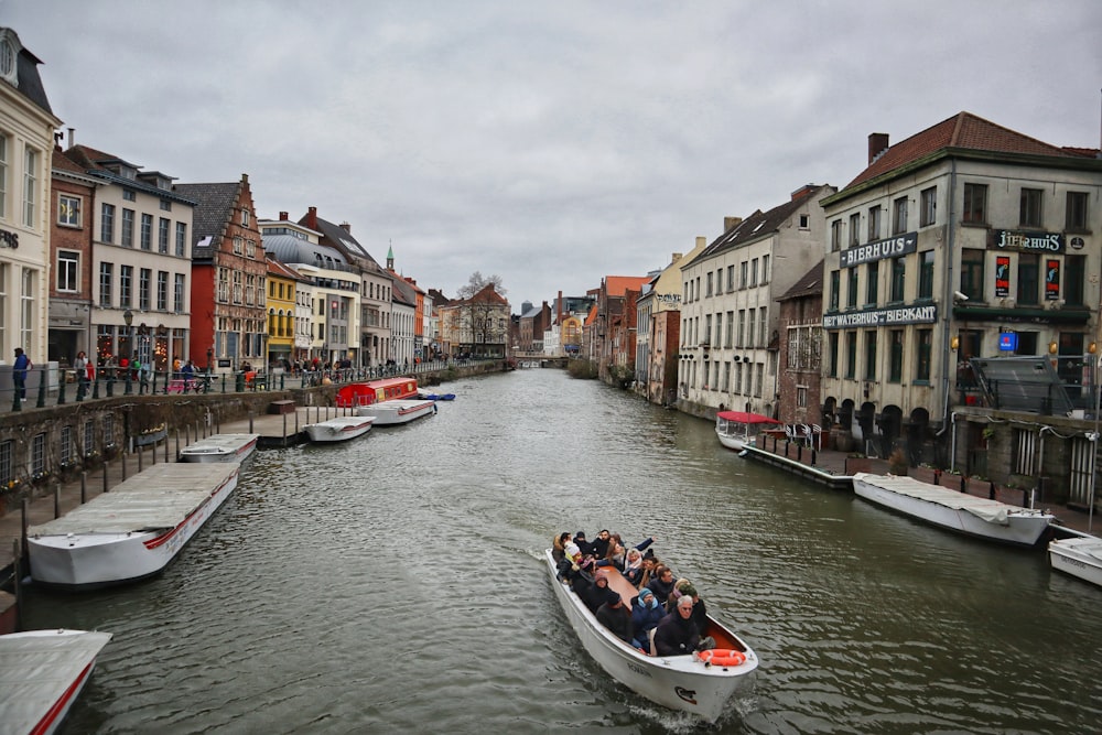 people riding on boat on river between buildings during daytime