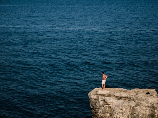 woman in white dress standing on rock formation near body of water during daytime in Tyulenovo Bulgaria