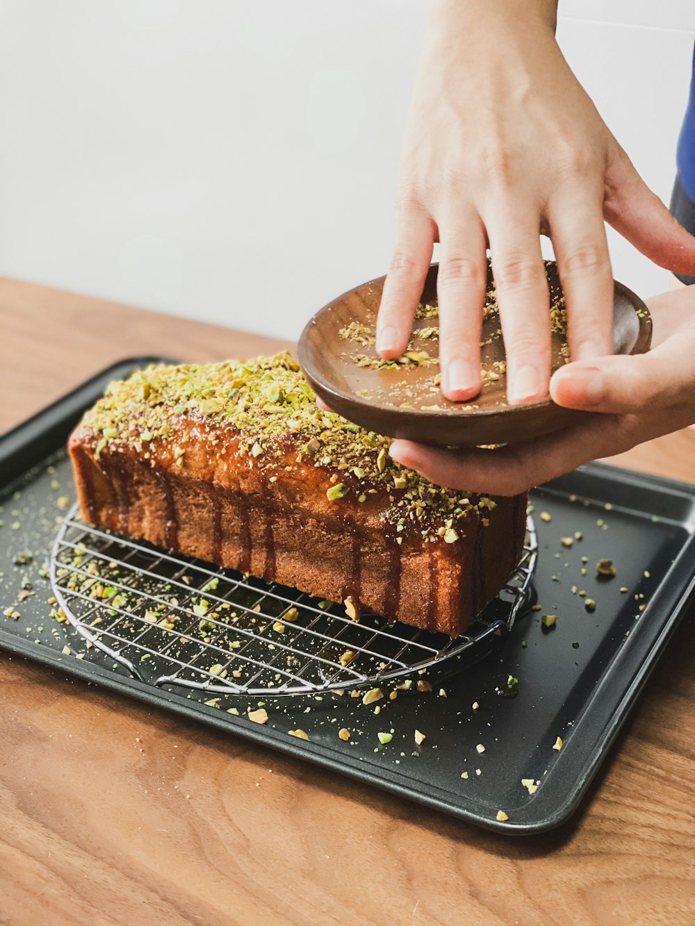 person holding brown pastry on black rectangular tray