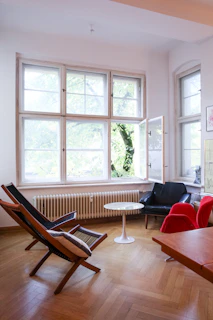 Bright living area with comfy chairs and a large window overlooking greenery.