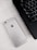 A silver smartphone lying flat on a light-colored wooden surface, positioned next to a black laptop keyboard.