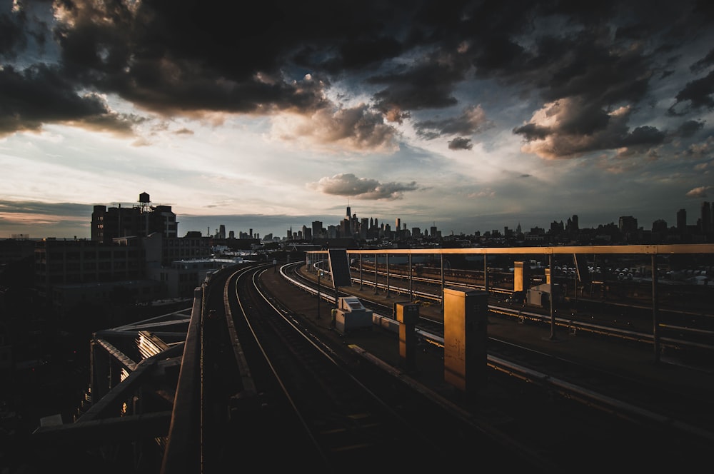 train rail under cloudy sky during daytime