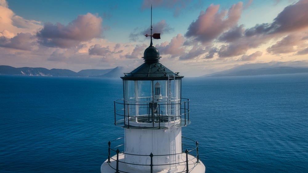 white and black lighthouse on blue sea under white clouds during daytime