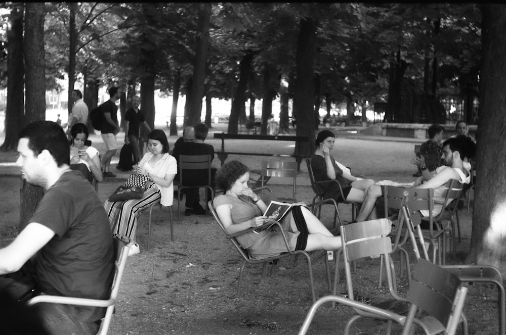 grayscale photo of people sitting on chair