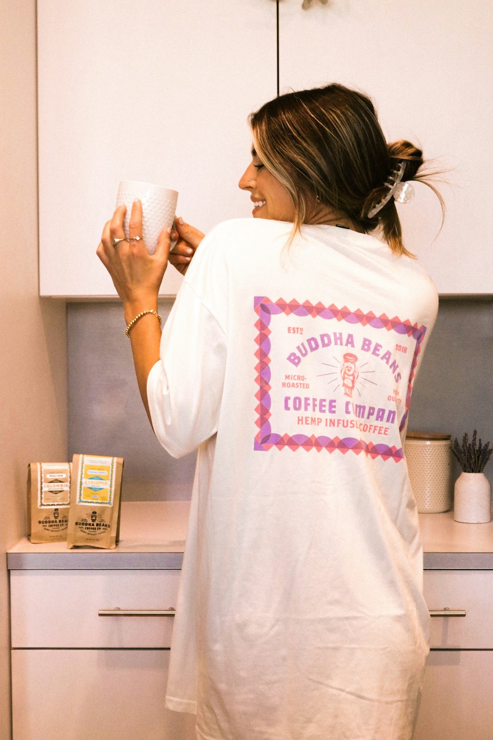 woman in white crew neck t-shirt holding white ceramic mug