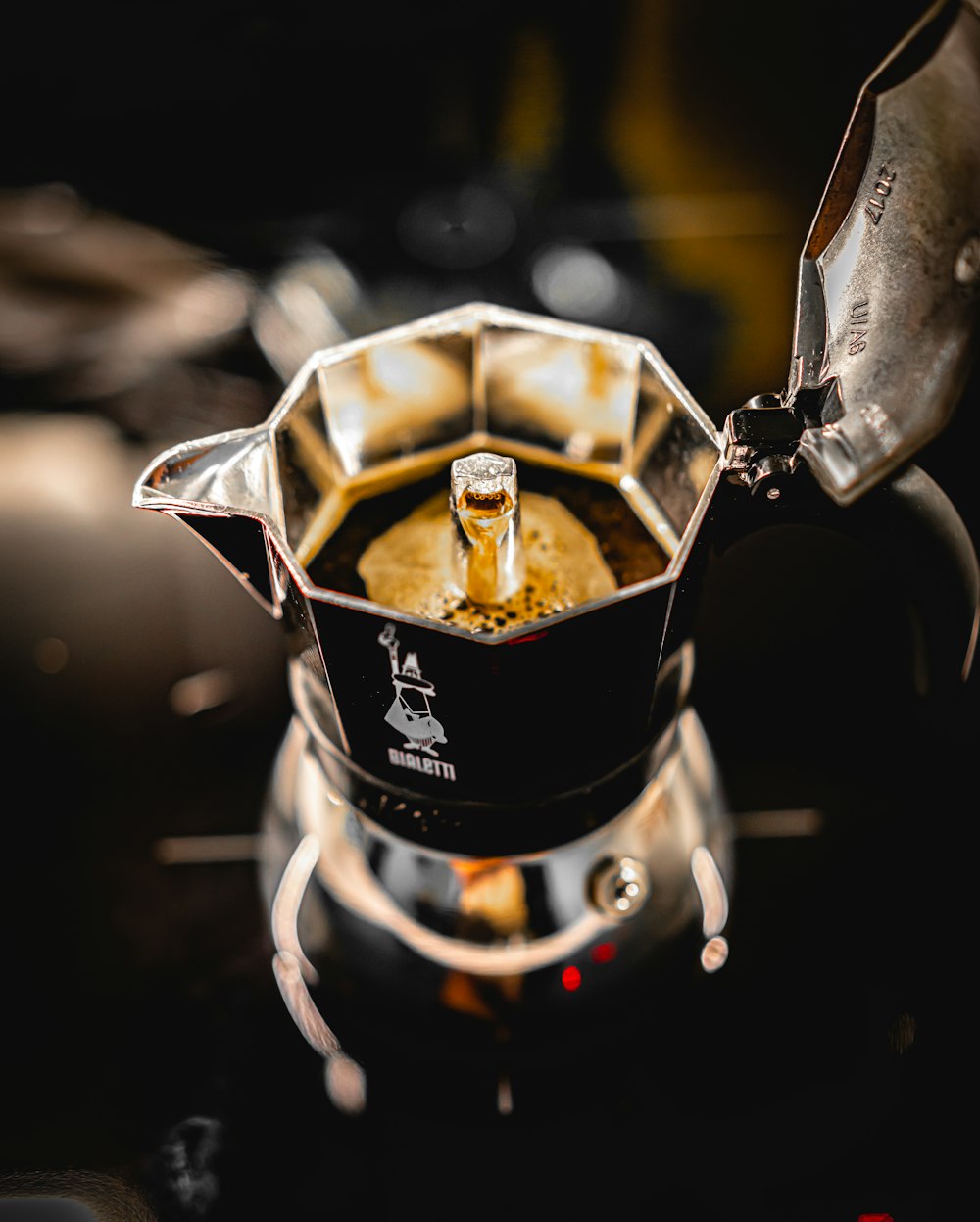 silver coffee pot pouring on clear glass cup