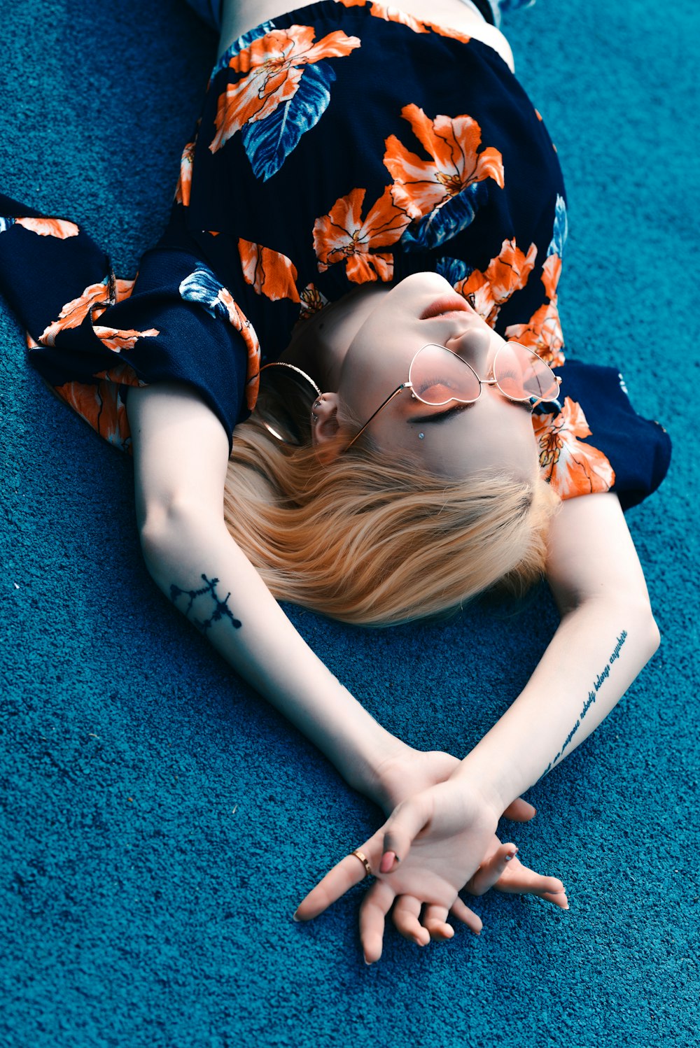 woman in black and blue floral dress lying on green textile