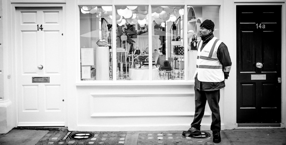 man in white and black jacket standing in front of glass window