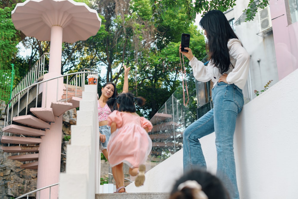 woman in white long sleeve shirt and blue denim jeans holding smartphone