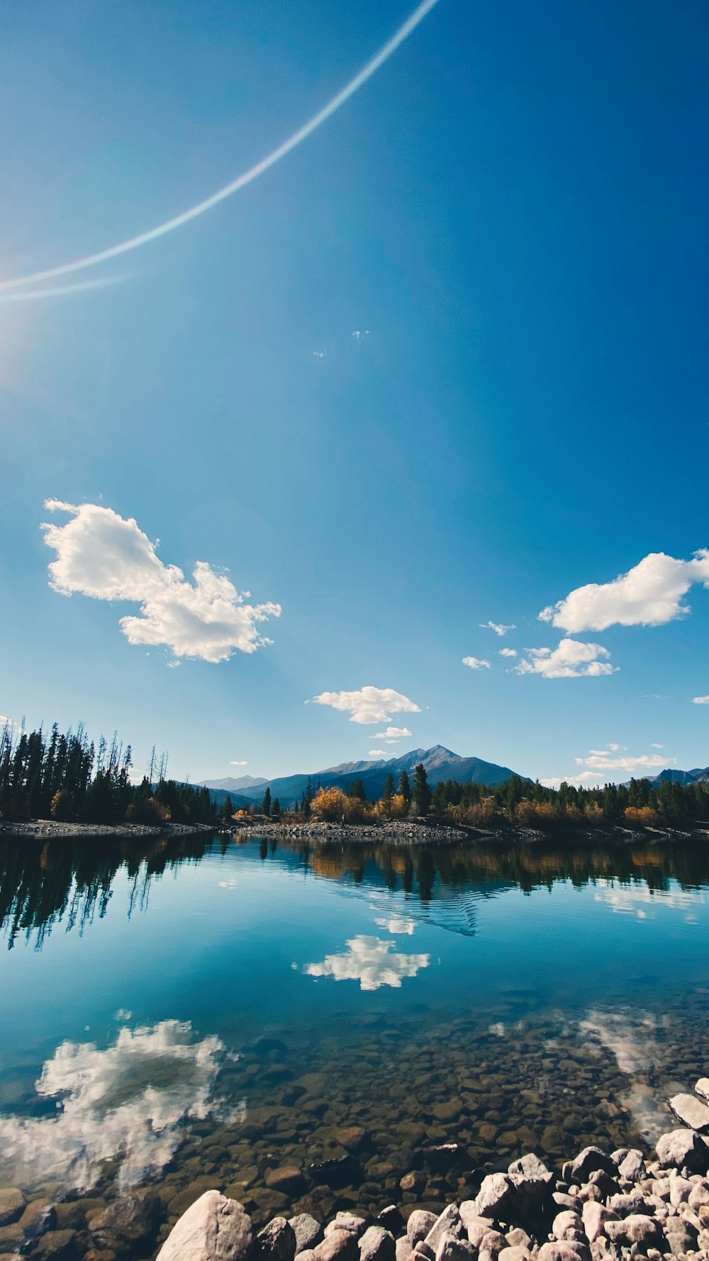 blue lake surrounded by trees under blue sky and white clouds during daytime