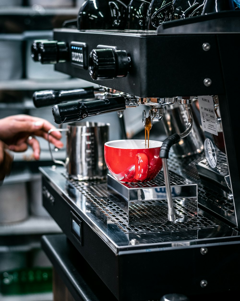 a red coffee cup being filled with liquid