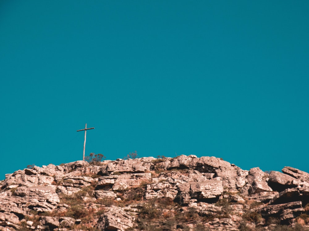 cross on top of brown rock formation under blue sky during daytime