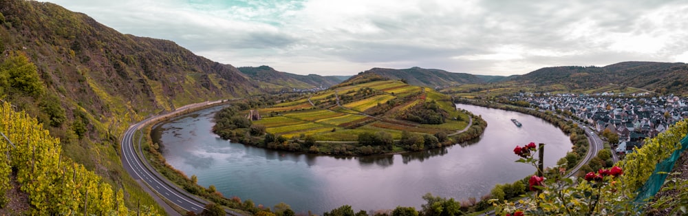 green and brown mountains beside lake under white clouds during daytime