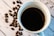A steaming cup of coffee placed on a rustic wooden table with coffee beans scattered around.
