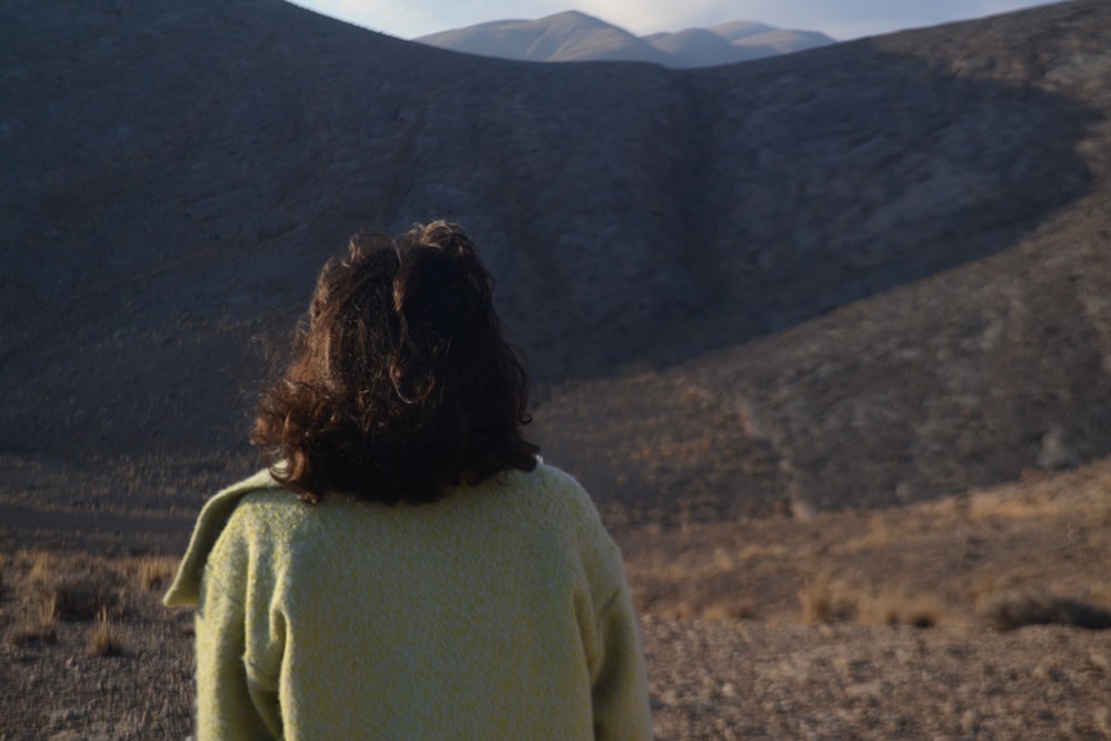 woman in yellow sweater standing on brown field during daytime