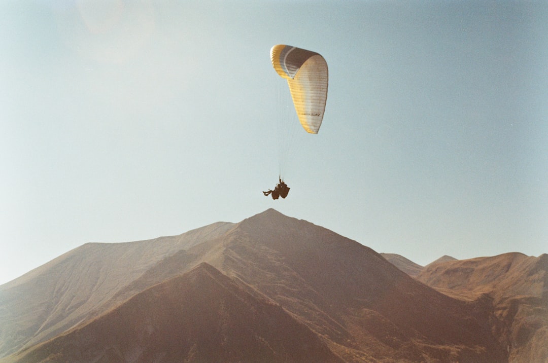 person in parachute over the mountain during daytime