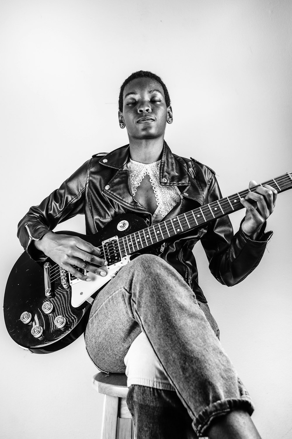 man in black leather jacket playing electric guitar