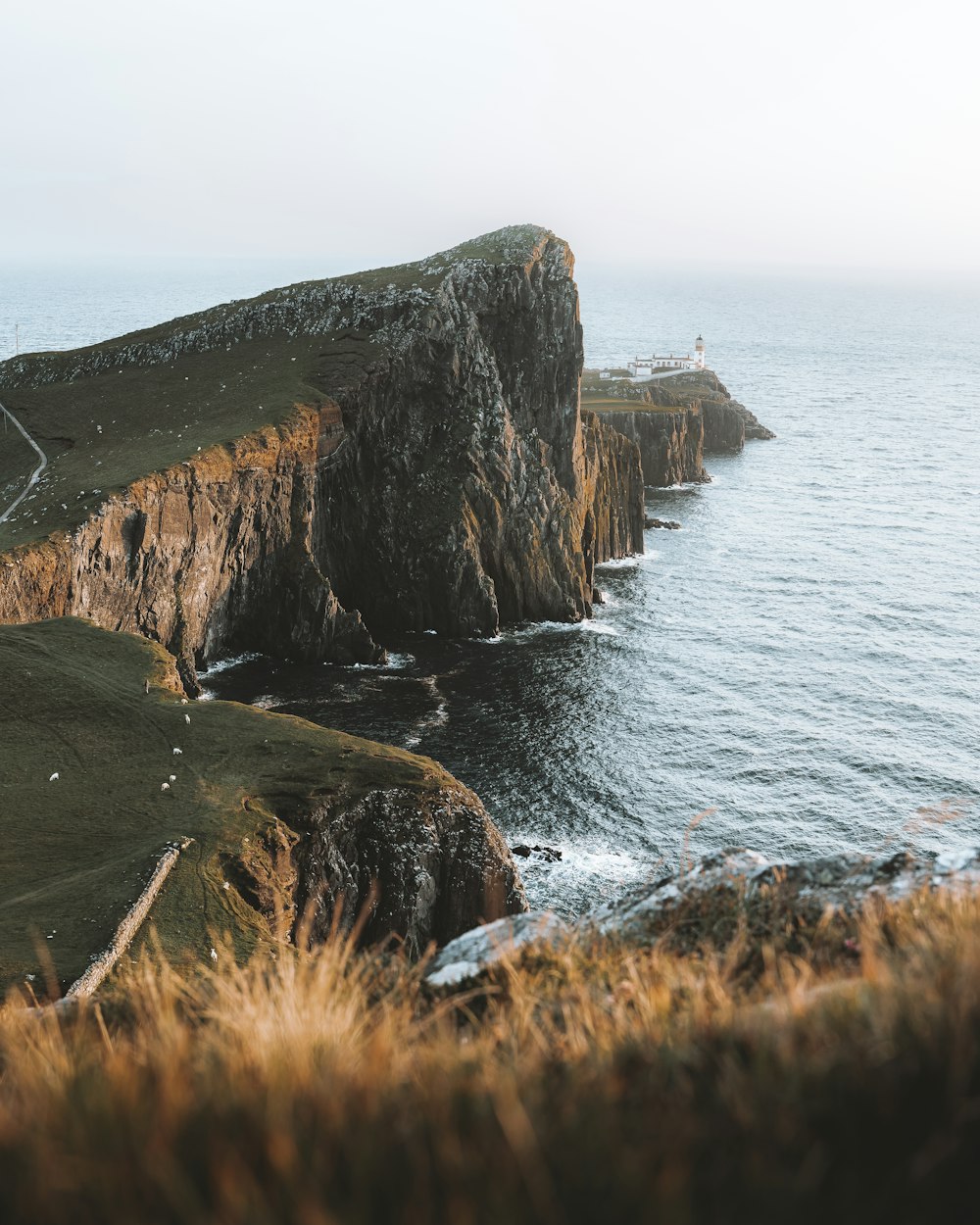 formazione rocciosa marrone e verde accanto al mare durante il giorno