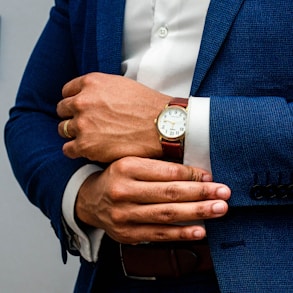 man in blue suit jacket wearing gold round analog watch