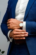 man in blue suit jacket wearing gold round analog watch