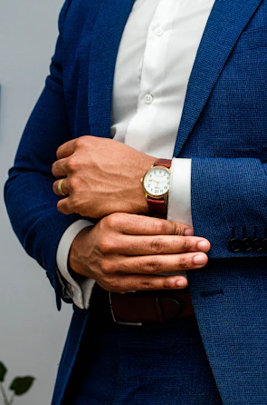 man in blue suit jacket wearing gold round analog watch