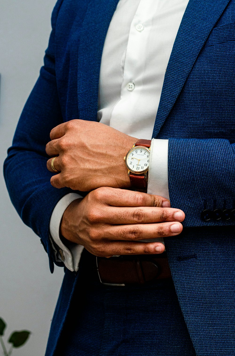 Hombre en chaqueta de traje azul con reloj analógico redondo dorado