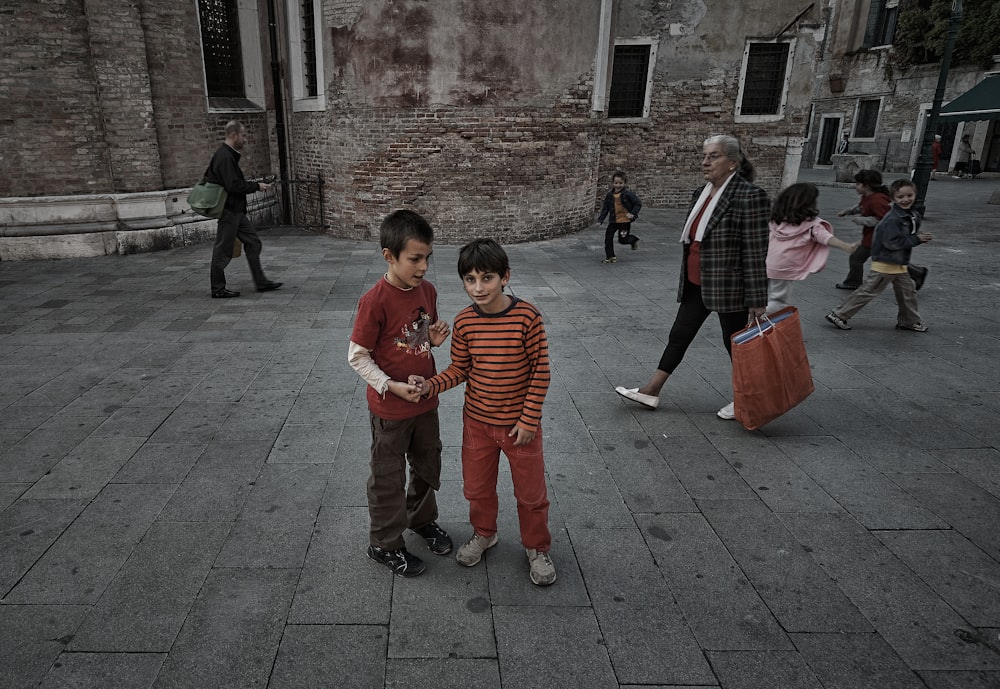 낮 동안 회색 콘크리트 바닥에 서 있는 아이들
