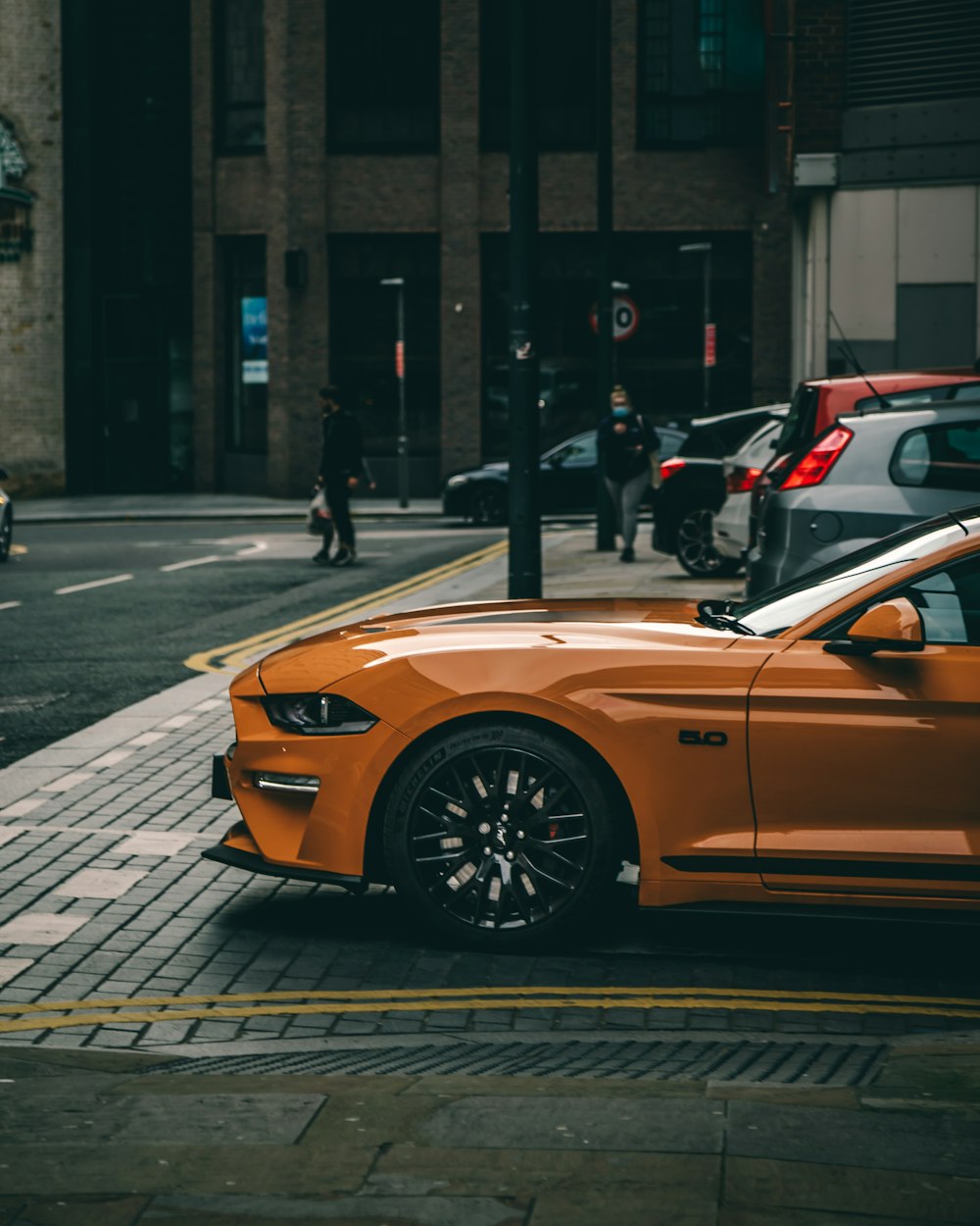 orange car parked on sidewalk during daytime