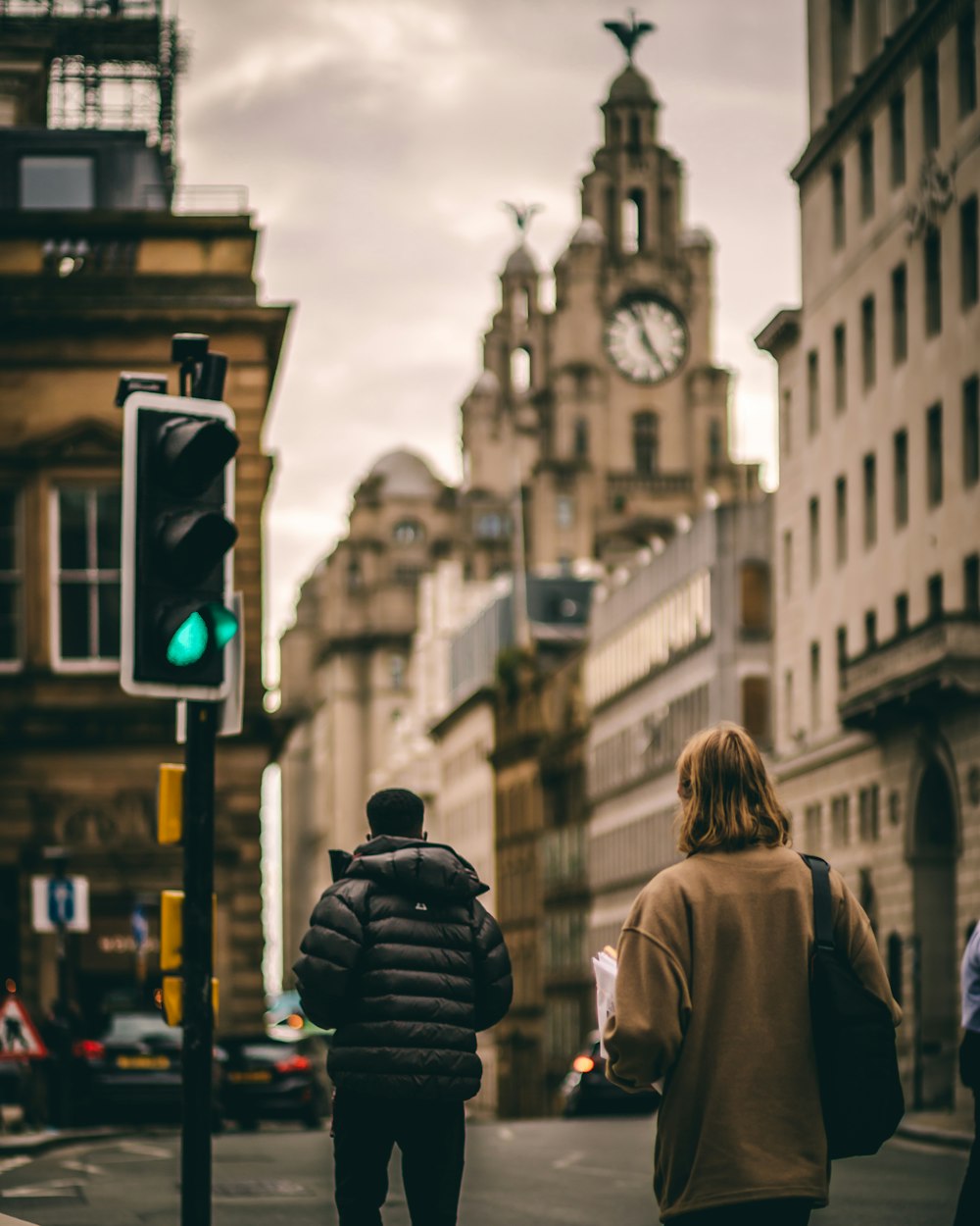 woman in brown coat standing near traffic light during daytime