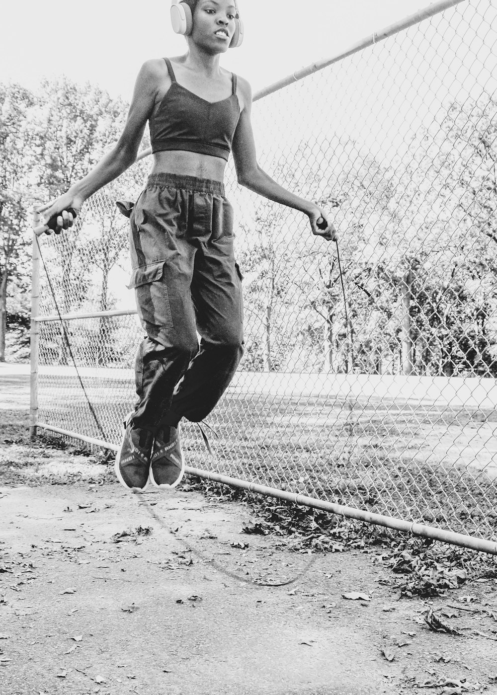 Hombre con camiseta negra sin mangas y jeans de mezclilla grises jugando a andar en patineta