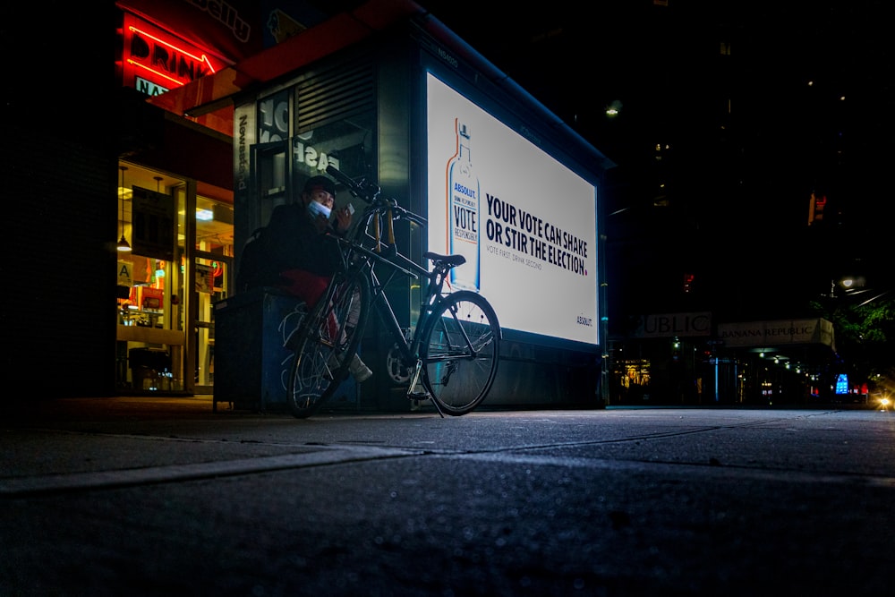 Bicicleta Black City estacionada junto al edificio azul y blanco durante la noche