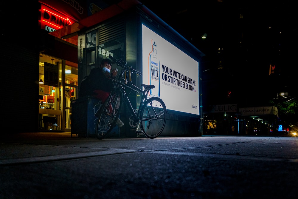 black city bike parked beside blue and white building during nighttime