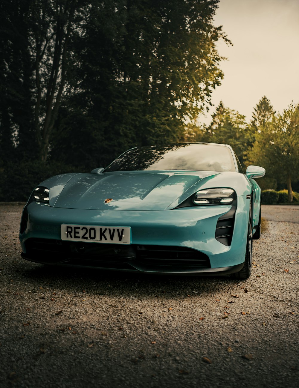 blue porsche 911 parked on dirt road near trees during daytime