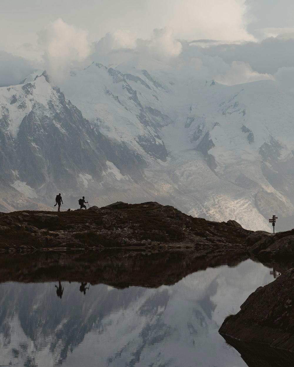 pessoa em pé na formação rochosa marrom perto do lago durante o dia