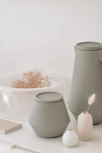 Minimalist organic vases and warm-toned cushions displayed against a neutral beige backdrop.