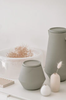 Minimalist organic vases and warm-toned cushions displayed against a neutral beige backdrop.