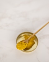 Close-up of golden desi ghee in a rustic clay pot with a wooden spoon.