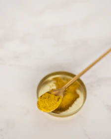 Close-up of golden homemade desi ghee in a rustic clay pot with a wooden spoon.
