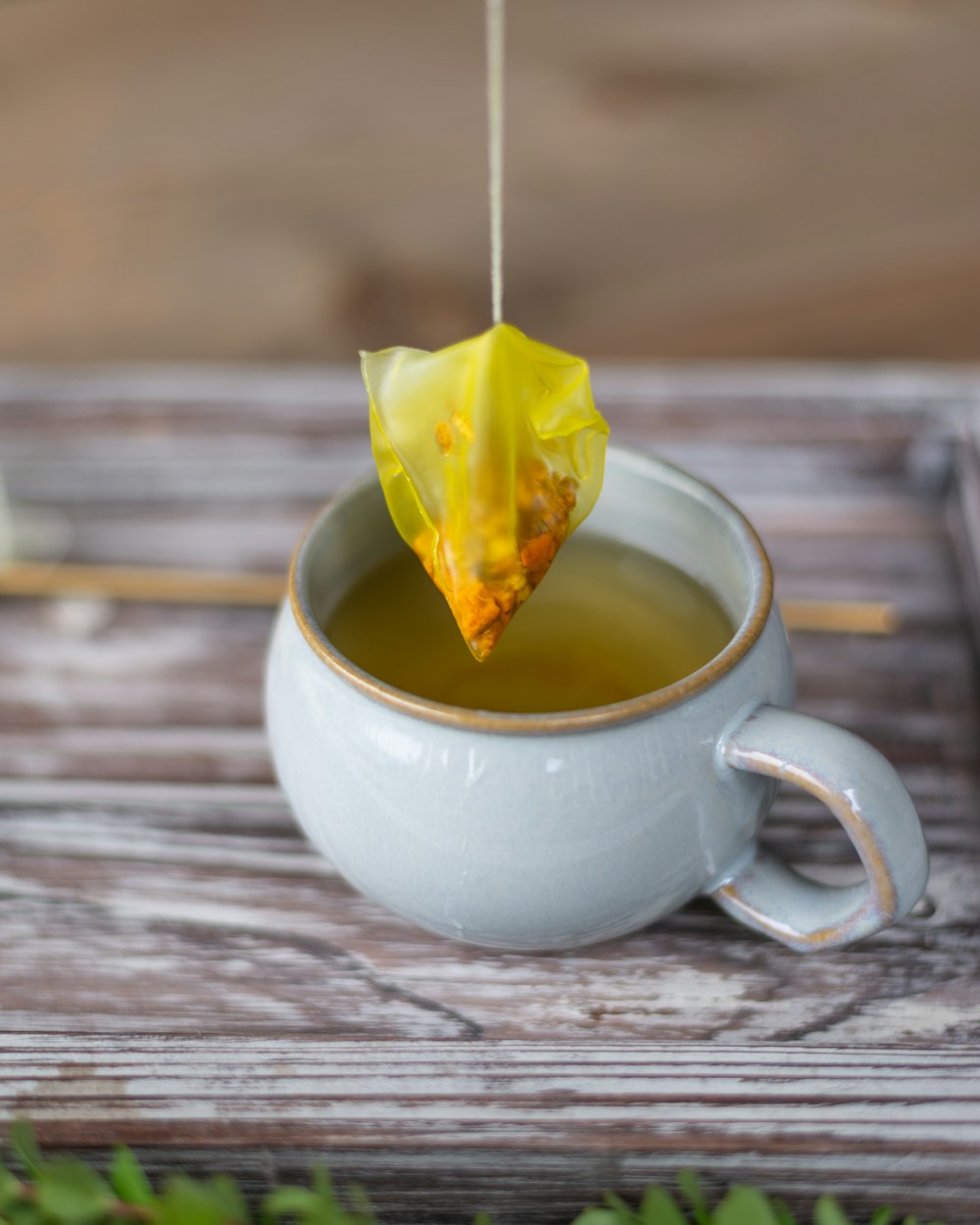 weiße Keramik-Teetasse mit gelbem Blatt darauf