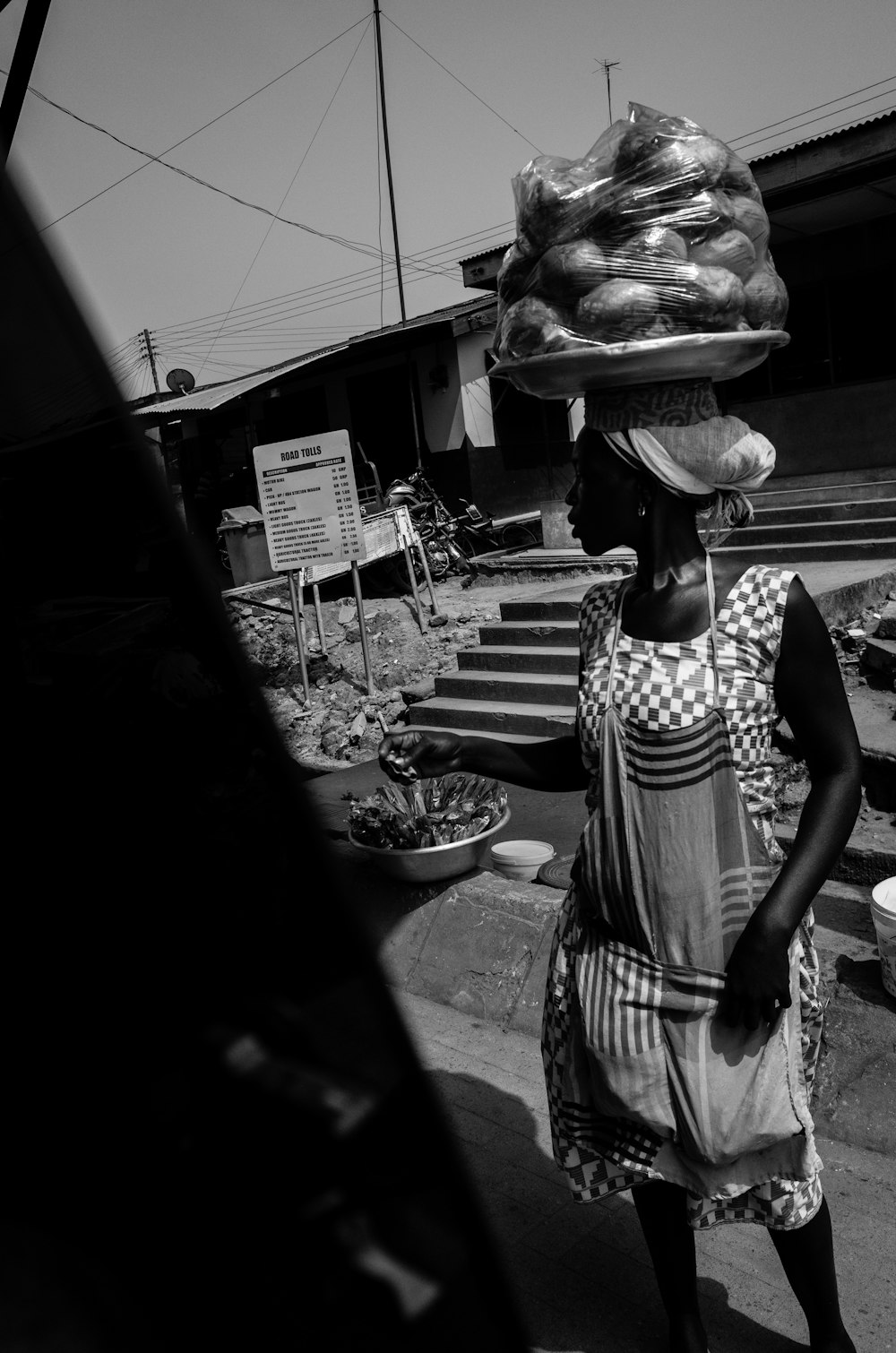 grayscale photo of woman in black and white stripe dress standing near table