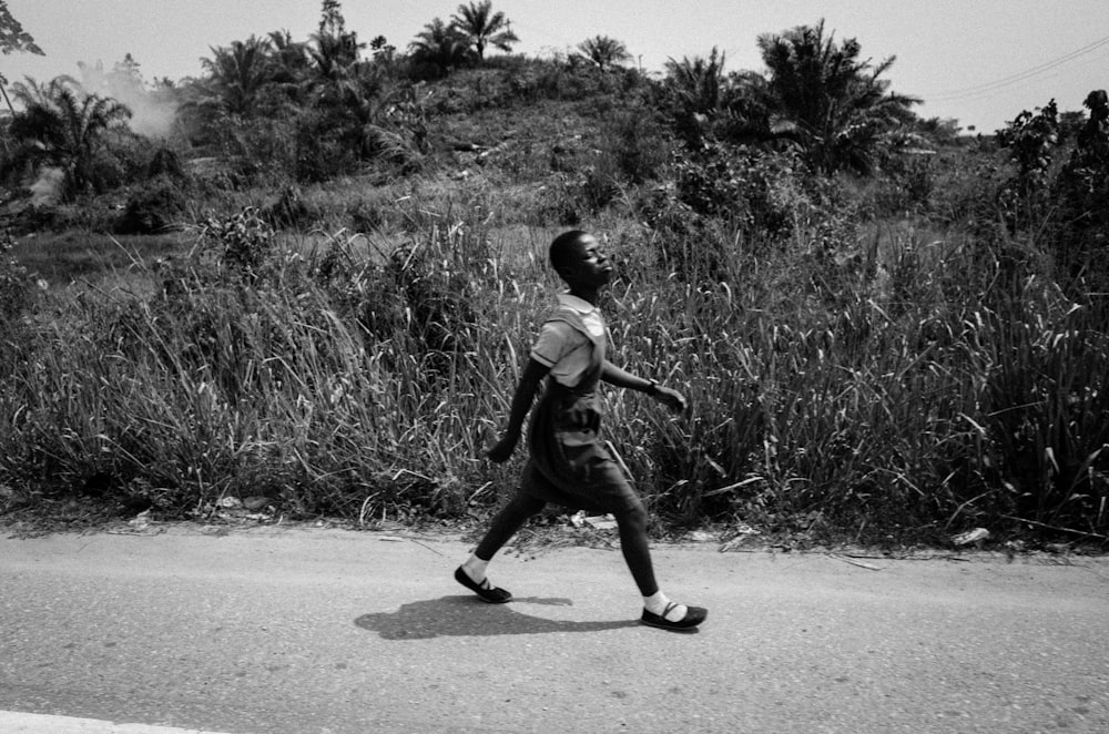 grayscale photo of boy in t-shirt and shorts playing basketball