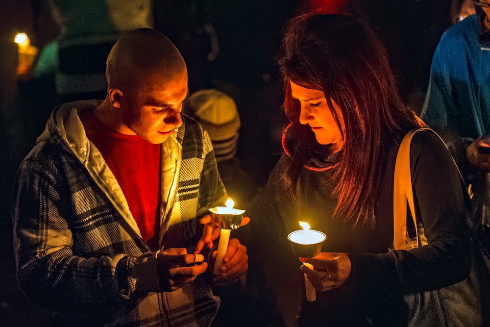 hombre y mujer sosteniendo velas encendidas