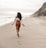 woman in white shirt walking on beach during daytime