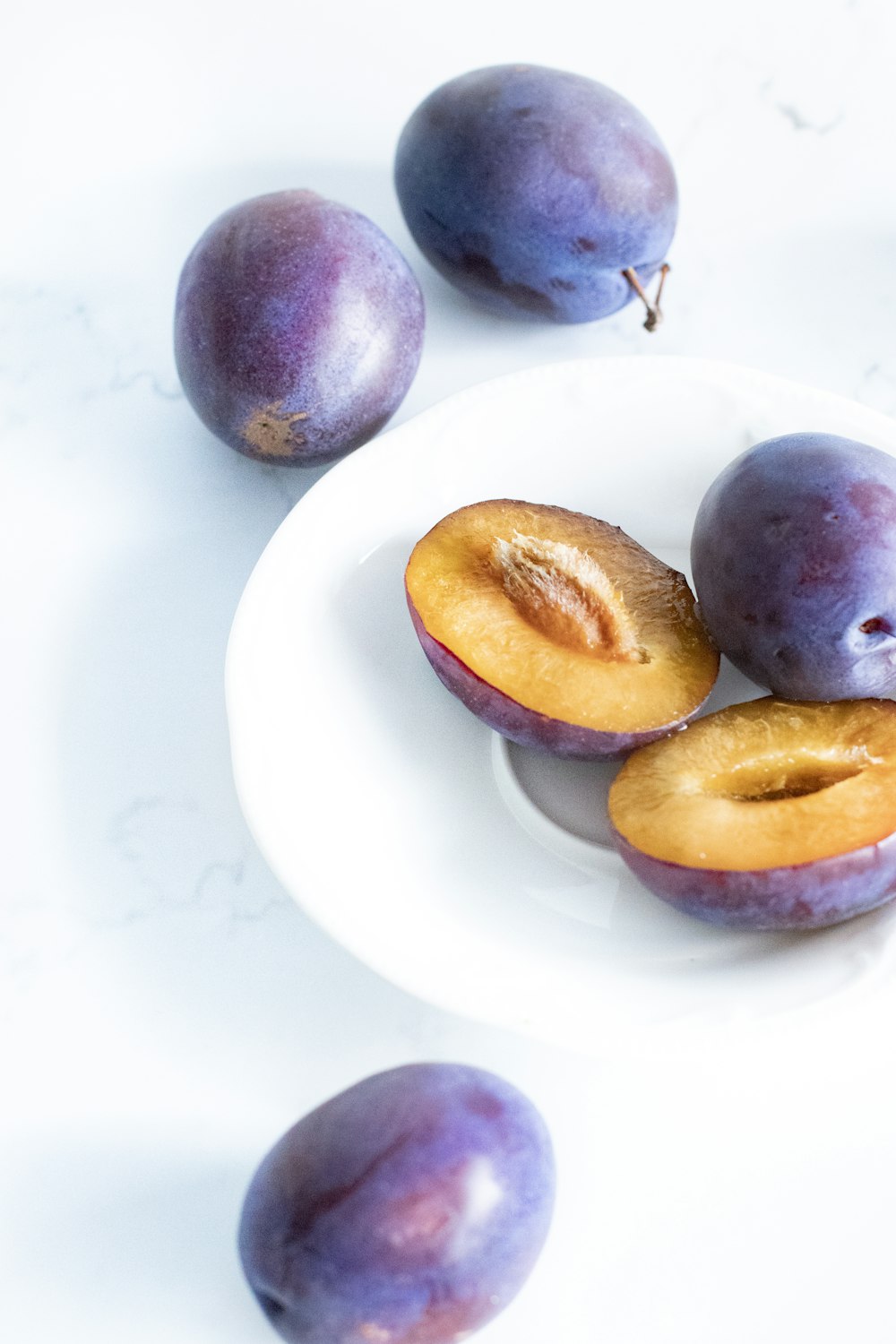 purple and yellow round fruits on white ceramic plate